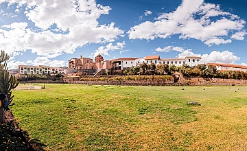 Cusco vista panorámica con cielo azul y nubes, jardines amplios y arquitectura colonial al fondo