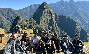 Foto grupal de viajeros en Machu Picchu con vista a Huayna Picchu